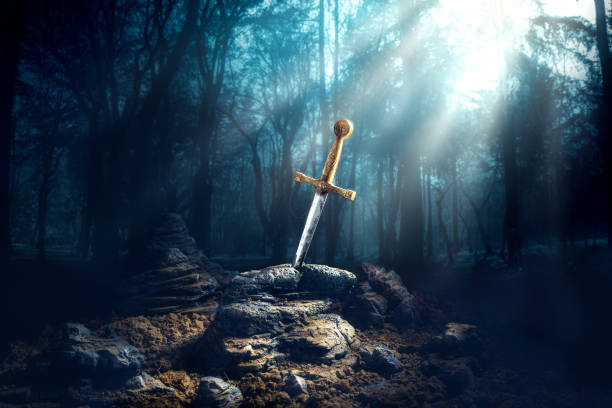 sword in the stone excalibur High contrast image of Excalibur, sword in the stone with light rays and dust specs in a dark forest sword photos stock pictures, royalty-free photos & images