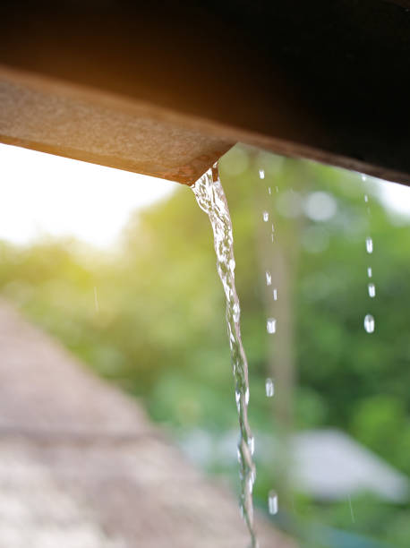 istock Rain pouring off roof against nature background. 907929042