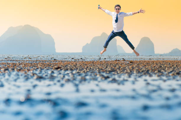 istock Relaxing Businessman using  laptop and smartphone on the beach 907930650