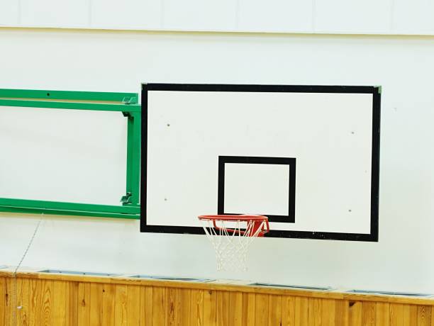 istock Old worn basketball hoop and  white shool gym wall 907930856