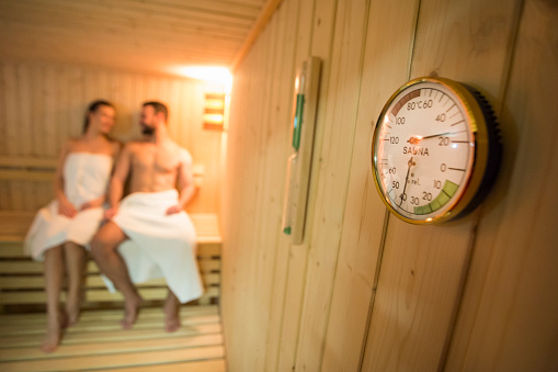 Young couple relaxing in a Finnish sauna. Unrecognizable Caucasian people.