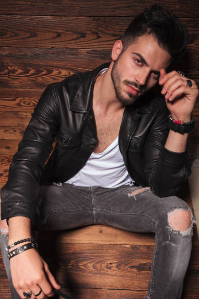 istock man in leather jacket and jeans sitting on wooden background 907933142