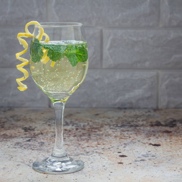 istock Spritzer cocktail with white wine, mint and ice, decorated with spiral lemon zest, square format 907933826