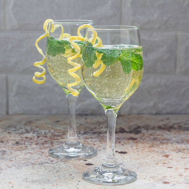 istock Spritzer cocktail with white wine, mint and ice, decorated with spiral lemon zest, square format 907933832