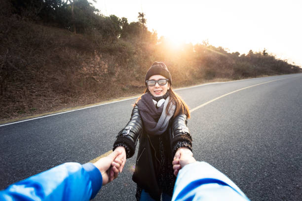 istock happy girlfriend holding boyfriend hands at mountain highway 907935800