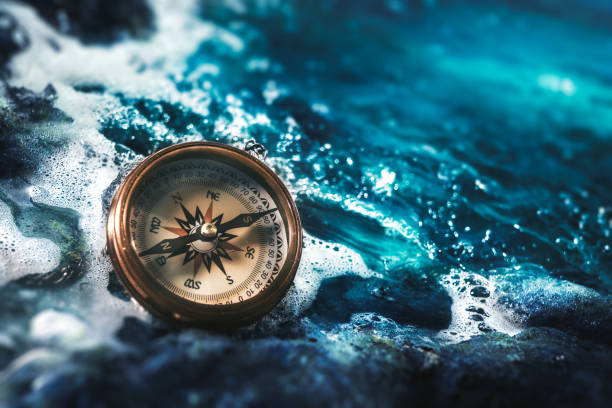 compass on rocks with a dark sky stock photo