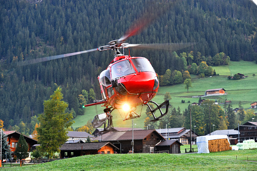An Ecureuil H125A helicopter hovering over a runway in rural Switzerland