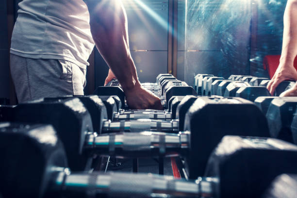 istock Young man exercising with weight in the gym. 907937388
