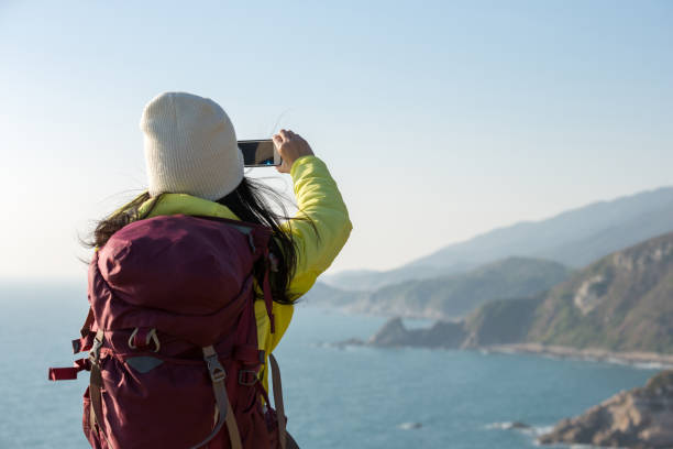 istock Young Woman Hiker Using Smartphone taking photo at Seaside 907937454