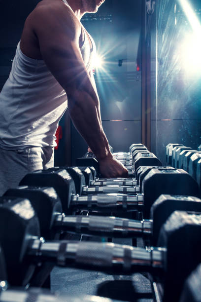 istock Young man exercising with weight in the gym. 907937574