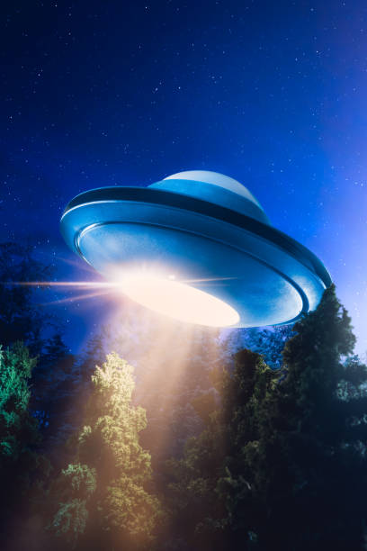 istock High contrast image of UFO flying over a forest with light beam at night 907937592