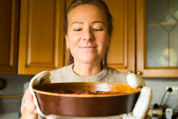 istock Young woman holding a baking tray with a ready cake 907939252