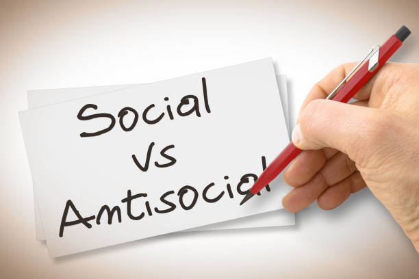 istock Hand writing Social Vs Antisocial with a pencil on a blank sheet - concept image 907940660