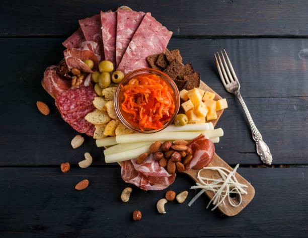 istock Assorted from meat and cheese on a chopping board. Smoked sausage, meat roll from a turkey with cheese, jamon, olives, nuts and various grades of cheese. Mediterranean traditional snack. Top view 907944706