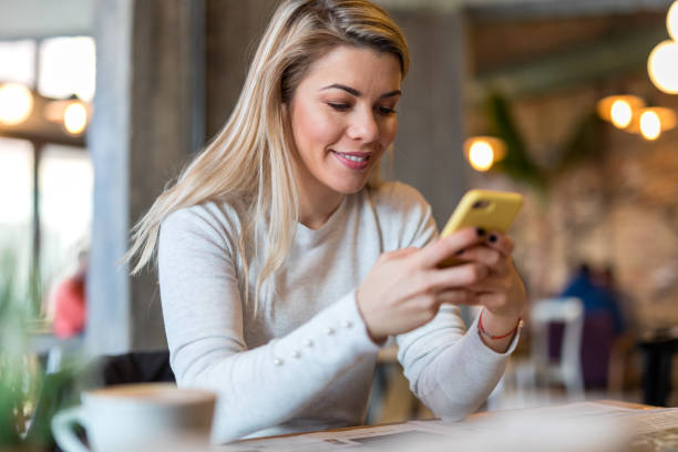 istock Young woman texting in coffee shop 907945036