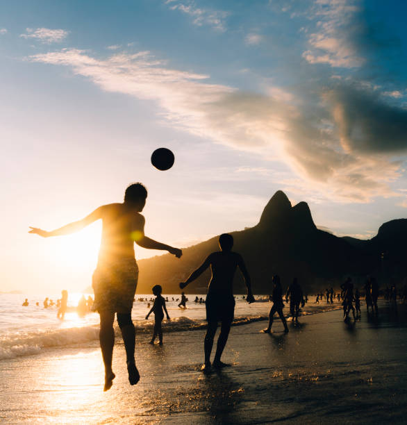 Great concept of soccer, man playing soccer on the beach in golden hour, sunset. Making keepie uppie.