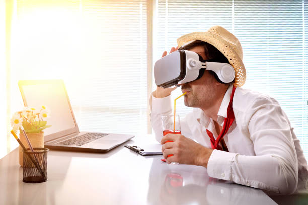 istock Man at work imagining his vacation with vr glasses drinking 907948992