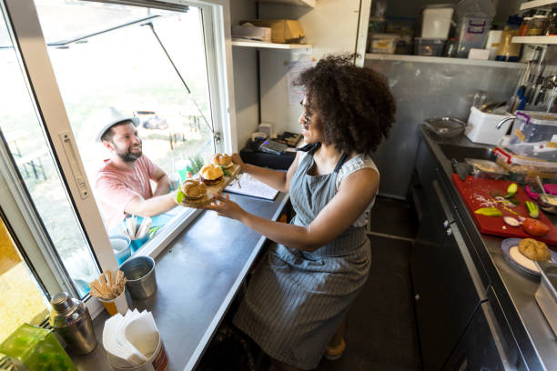 istock Smiling food van worker offering sandwiches 907950244