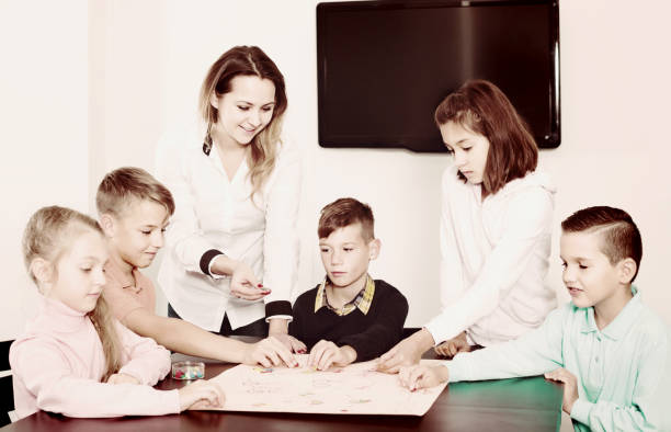 istock Children making move on pre-marked surface of board game 907953560