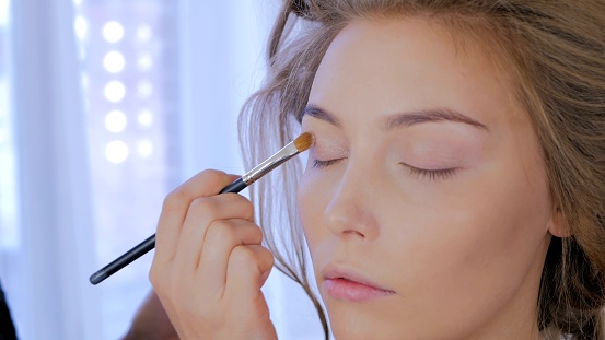 Professional make-up artist applying cream base eyeshadow primer to model eye. Beauty, makeup and fashion concept