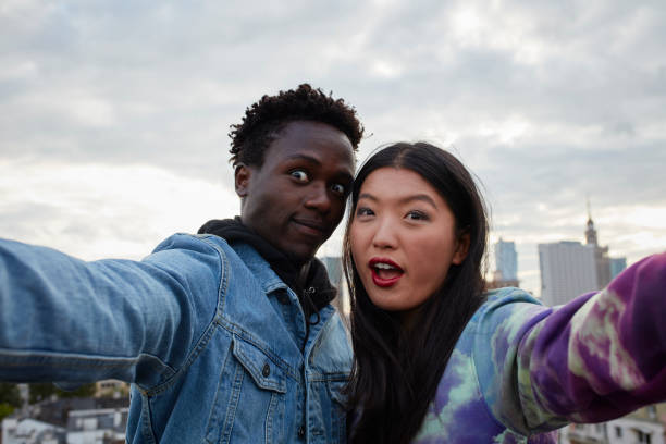 istock Multi ethnic couple hugging on the rooftop. Making selfie 907956058