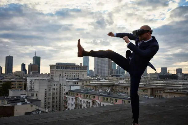 Young businessman in VR karate pose. Cityscape in the background