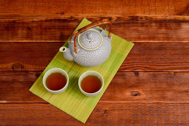 chinesische tee-set auf einer bambusmatte auf einem grob strukturierten braunen tisch. - jasmine tea black tea tea drink stock-fotos und bilder