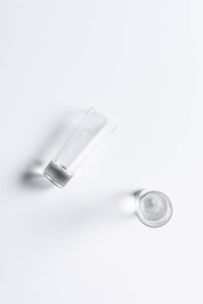 istock one glass with water and one empty glass on white table 907959046