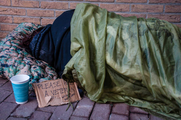 hogar femenino veterano para dormir contra el edificio de ladrillo - interés humano fotografías e imágenes de stock