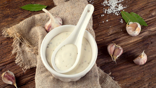 Bowl of Garlic sauce or mayonnaise Bowl of Garlic sauce or mayonnaise on a wooden board. savoury sauce stock pictures, royalty-free photos & images