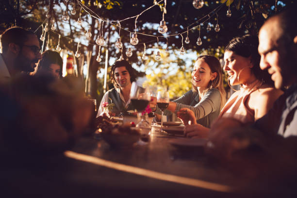 Friends celebrating with wine and food at rustic countryside party Young elegant friends having mediterranean party with food and drink at countryside cottage in Italy restaurant france stock pictures, royalty-free photos & images