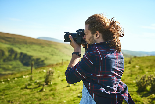 Shot of a man taking photographs with his camera outdoors