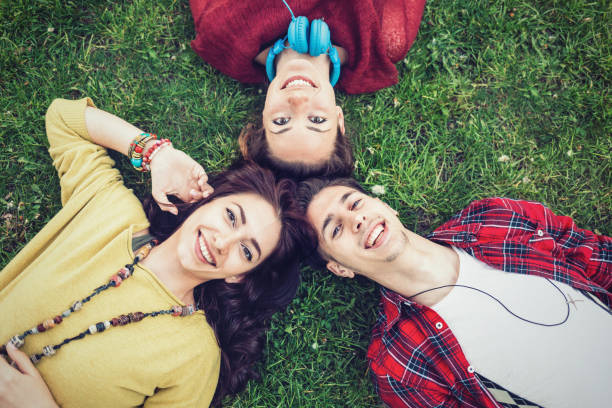 istock Three happy friends relaxing on the park lawn 907963632