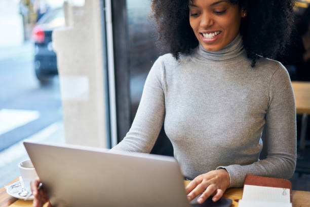 istock Cropped image of cheerful afro american copywriter searching information in websites while distantly working on laptop.Good looking businesswoman with curly hair planning working process indoors 907963782