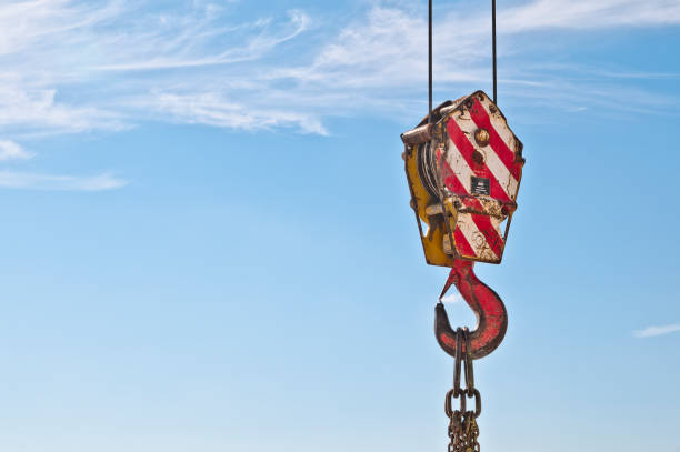 Lifting hook crane and chain links. Lifting hook for heavy loads. Tower  lifting  crane with steel hook building metal construction against clear blue sky. Hook a crane old rusty and high construction and chain links rigging stock pictures, royalty-free photos & images
