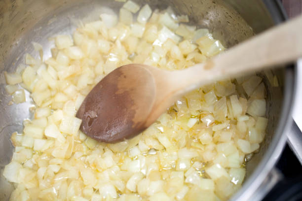 Pieces of onion frying, wooden spoon. stock photo