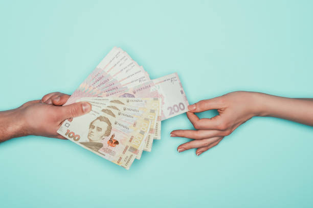 istock woman taking cash from man isolated on turquoise 907966604