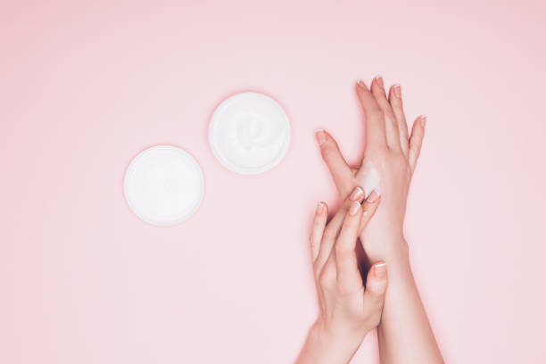 istock woman applying cream on hand isolated on pink 907966718