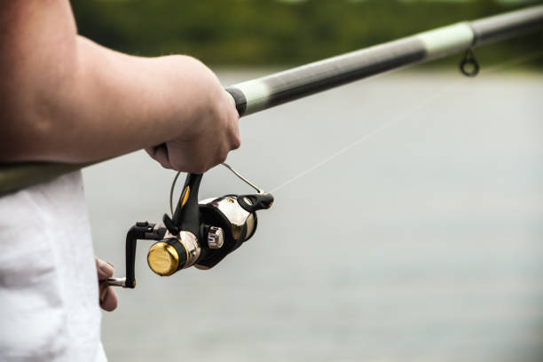istock hand holding the rod and reel 907966878