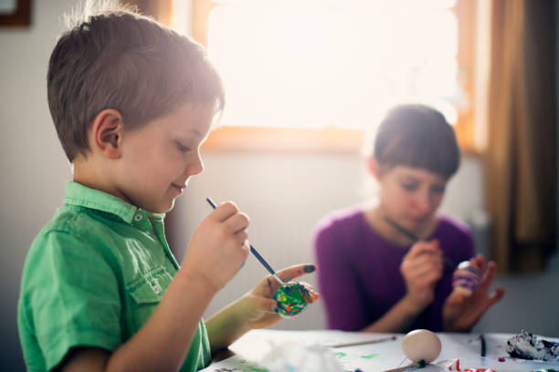 istock Brother and sister painting easter eggs 907967416