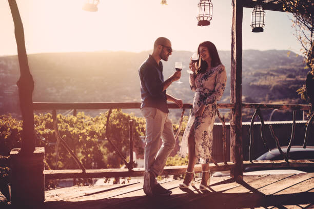 istock Elegant couple drinking red wine at French rustic vineyard winery 907967896
