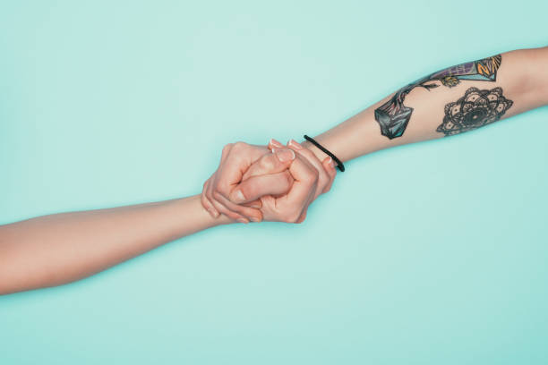 istock women holding hands isolated on turquoise 907968548
