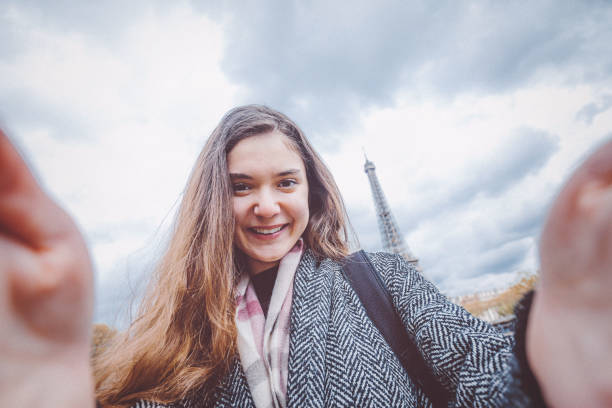 istock Young woman taking selfie with smartphone against Eiffel Tower 907968996