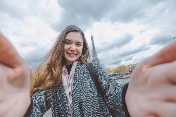 istock Young woman taking selfie with smartphone against Eiffel Tower 907969130