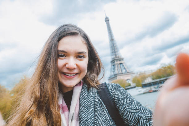 istock Young woman taking selfie with smartphone against Eiffel Tower 907969146