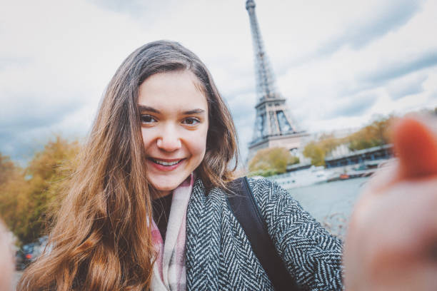istock Young woman taking selfie with smartphone against Eiffel Tower 907969282
