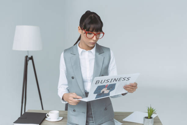 istock businesswoman reading newspaper isolated on gray 907969564