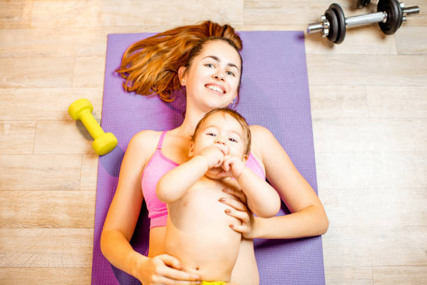 istock Mother with baby boy exercising on the floor 907971344