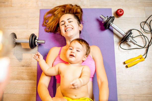 istock Mother with baby boy exercising on the floor 907971746
