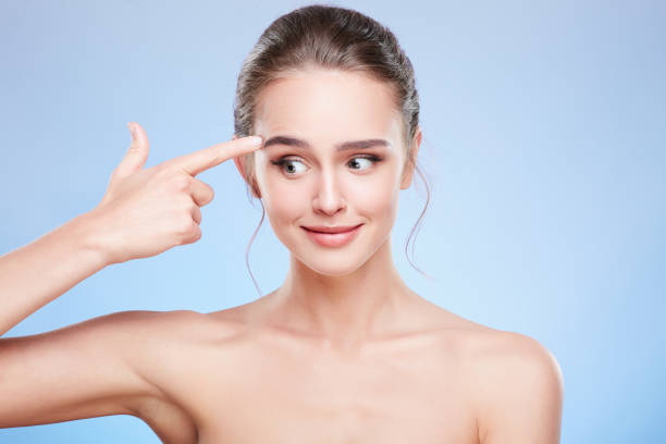 istock Embarrassed woman pointing at temple and looking aside 907972038